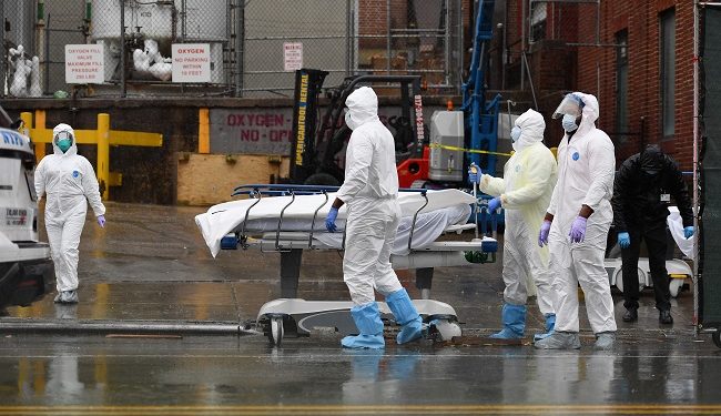 Medical personnel move a deceased patient to a refrigerated truck serving as make shift morgues at Brooklyn Hospital Center on April 09, 2020 in New York City. - America's coronavirus epicenter of New York recorded a new single-day high of 799 COVID-19 deaths Thursday but Governor Andrew Cuomo said the rate of hospitalizations continued to fall. (Photo by Angela Weiss / AFP)