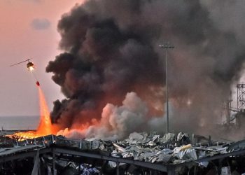 EDITORS NOTE: Graphic content / A helicopter puts out a fire at the scene of an explosion at the port of Lebanon's capital Beirut on August 4, 2020. (Photo by STR / AFP)