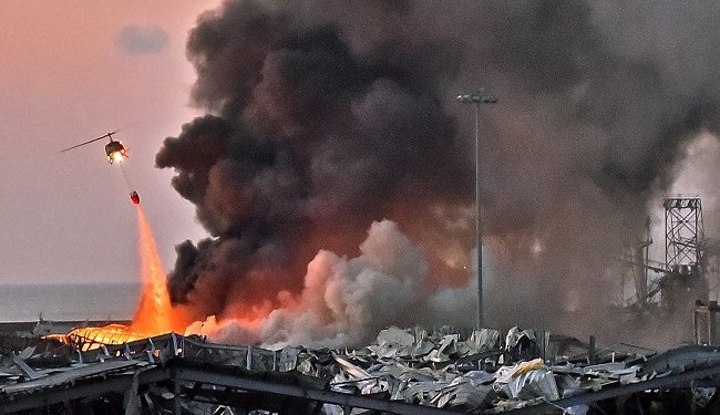 EDITORS NOTE: Graphic content / A helicopter puts out a fire at the scene of an explosion at the port of Lebanon's capital Beirut on August 4, 2020. (Photo by STR / AFP)