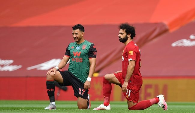 Aston Villa's Egyptian midfielder Trezeguet (L) and Liverpool's Egyptian midfielder Mohamed Salah (R) take a knee in support of the Black Lives Movement during the English Premier League football match between Liverpool and Aston Villa at Anfield in Liverpool, north west England on July 5, 2020. (Photo by Paul ELLIS / POOL / AFP) / RESTRICTED TO EDITORIAL USE. No use with unauthorized audio, video, data, fixture lists, club/league logos or 'live' services. Online in-match use limited to 120 images. An additional 40 images may be used in extra time. No video emulation. Social media in-match use limited to 120 images. An additional 40 images may be used in extra time. No use in betting publications, games or single club/league/player publications. /